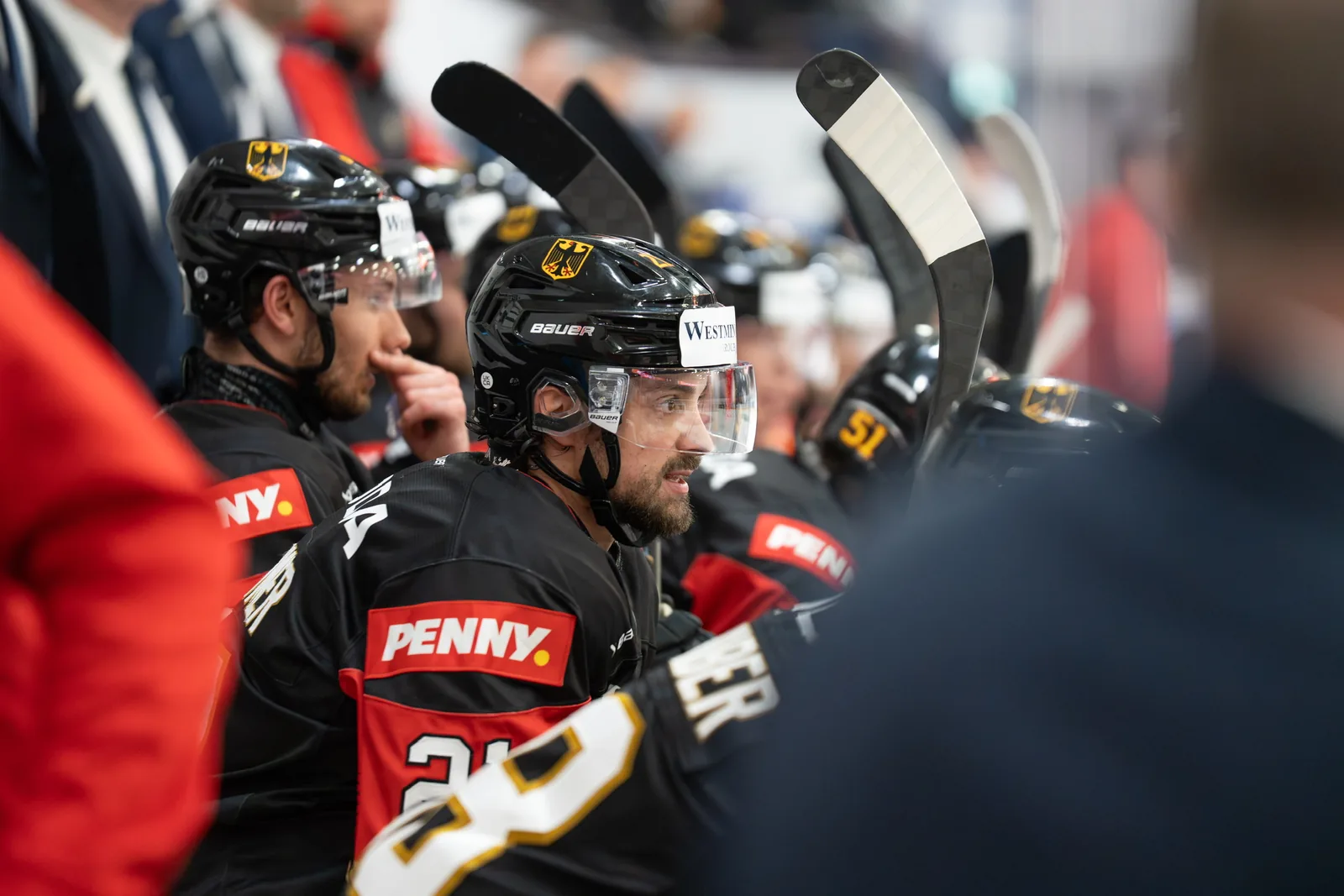 Eishockeyspieler stehen Schulter an Schulter auf der Spielerbank.